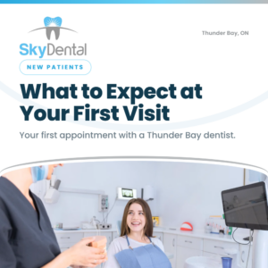 Smiling female patient in a dental bib talking with a dental assistant holding a tooth model, SkyDental New Patients blog cover: What to Expect at Your First Visit – your first appointment with a Thunder Bay dentist.